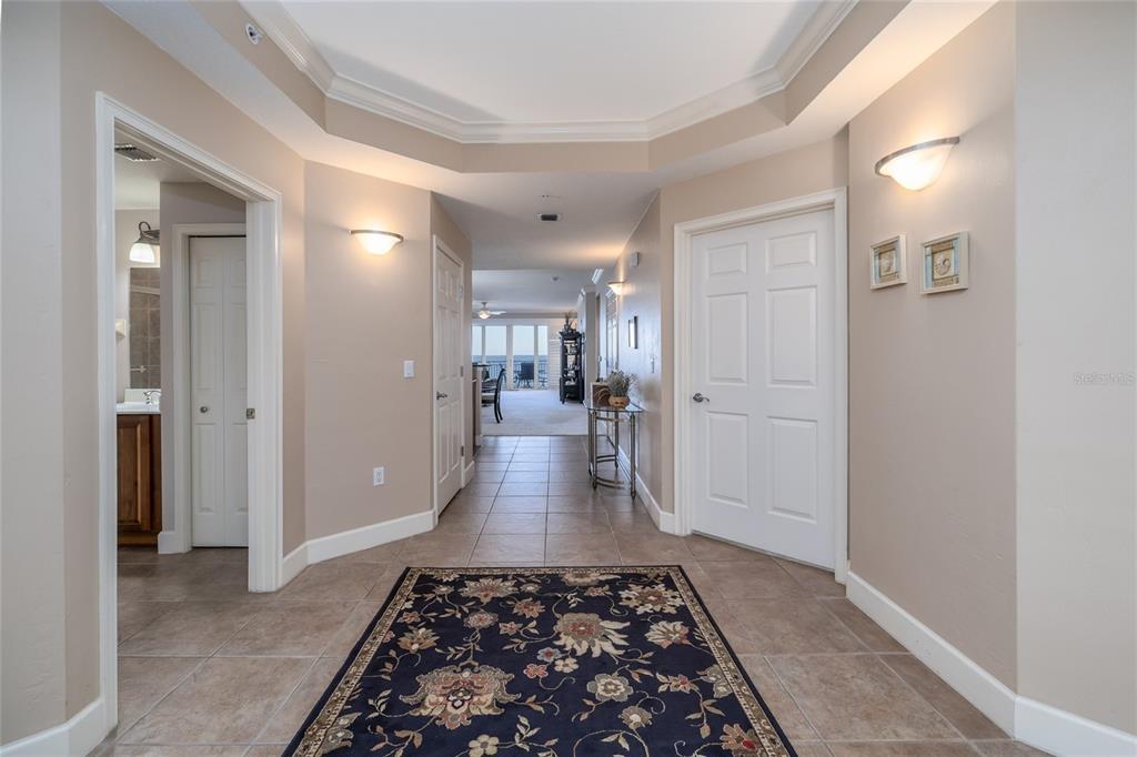 A tiled foyer features a dark floral rug, recessed ceiling, and a view toward the balcony — 2403 S ATLANTIC AVENUE UNIT 604, DAYTONA BEACH, FL