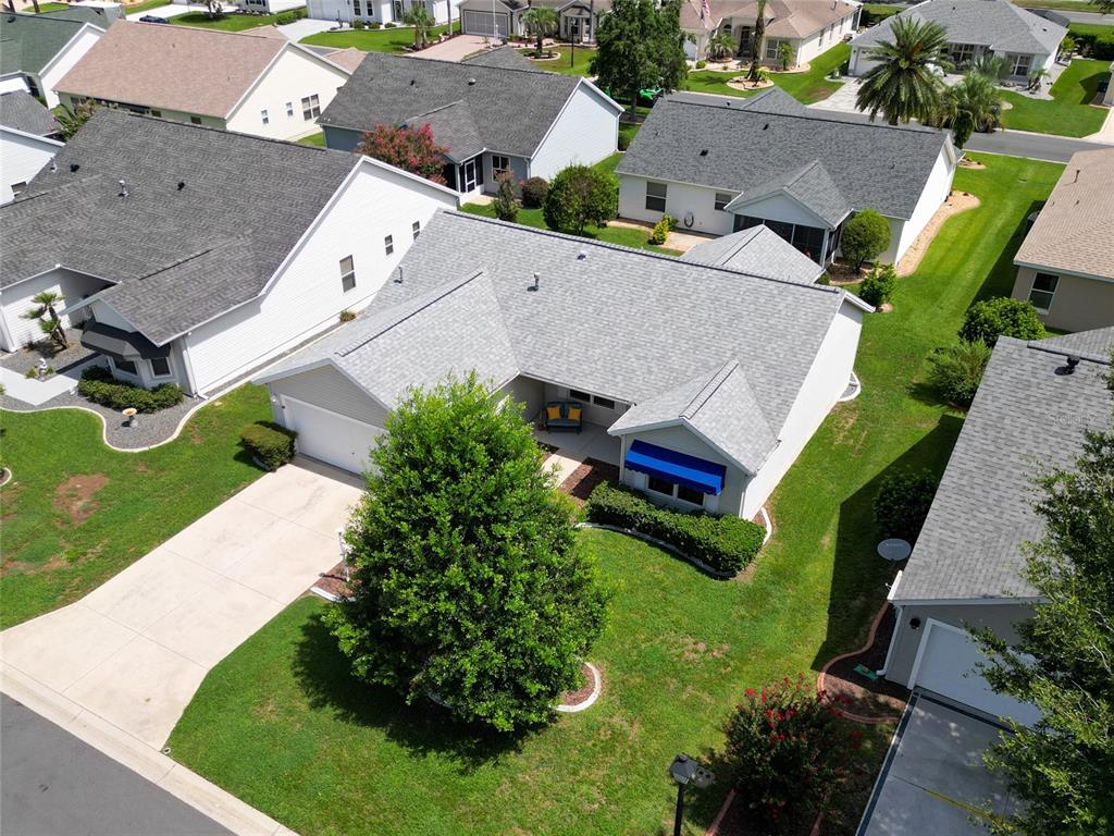 An aerial view shows a single-story suburban house with a gray roof and driveway — 2707 LA POSADA DRIVE, THE VILLAGES, FL