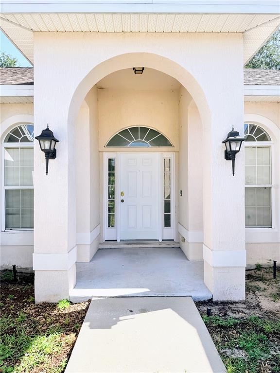The exterior of a house features a white arched entryway with a central front door — 6759 KRENSON OAKS CIRCLE, LAKELAND, FL
