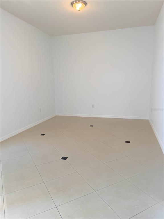 An empty room with white walls, a ceiling light, and light-colored tile flooring — 6759 KRENSON OAKS CIRCLE, LAKELAND, FL
