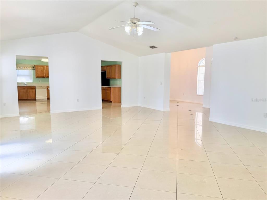 A spacious, open-concept living area features white walls, vaulted ceilings, and light-colored tile flooring — 6759 KRENSON OAKS CIRCLE, LAKELAND, FL