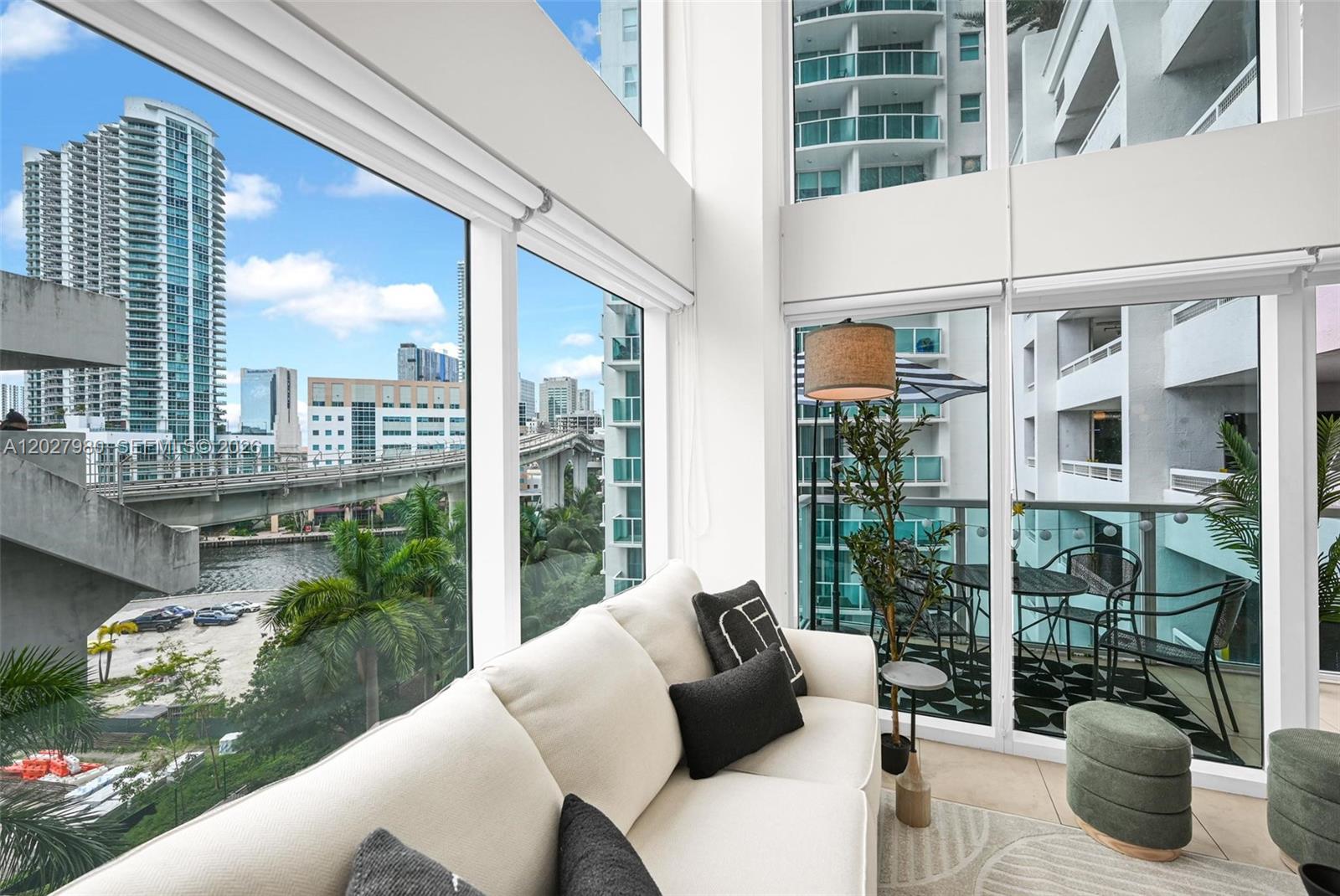 A living room with floor-to-ceiling windows overlooks a city skyline, a bridge, and a balcony — 41 SE 5th St # 517, Miami FL 33131, MIAMI, FL