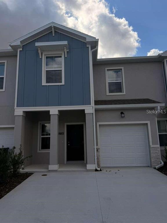 A two-story townhouse with a blue vertical-siding accent, a garage, and a concrete driveway — 2728 SKYLINE LOOP, KISSIMMEE, FL