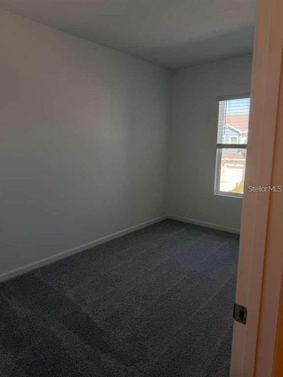 An empty bedroom features gray carpet, light gray walls, and a single window — 2728 SKYLINE LOOP, KISSIMMEE, FL