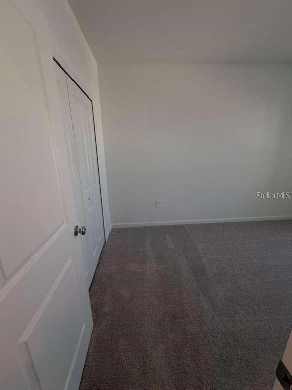 A bedroom with white walls, gray carpet, and a white bi-fold closet door — 2728 SKYLINE LOOP, KISSIMMEE, FL
