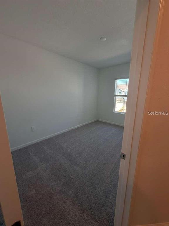 An empty bedroom with gray carpet, white walls, and a window with blinds — 2728 SKYLINE LOOP, KISSIMMEE, FL