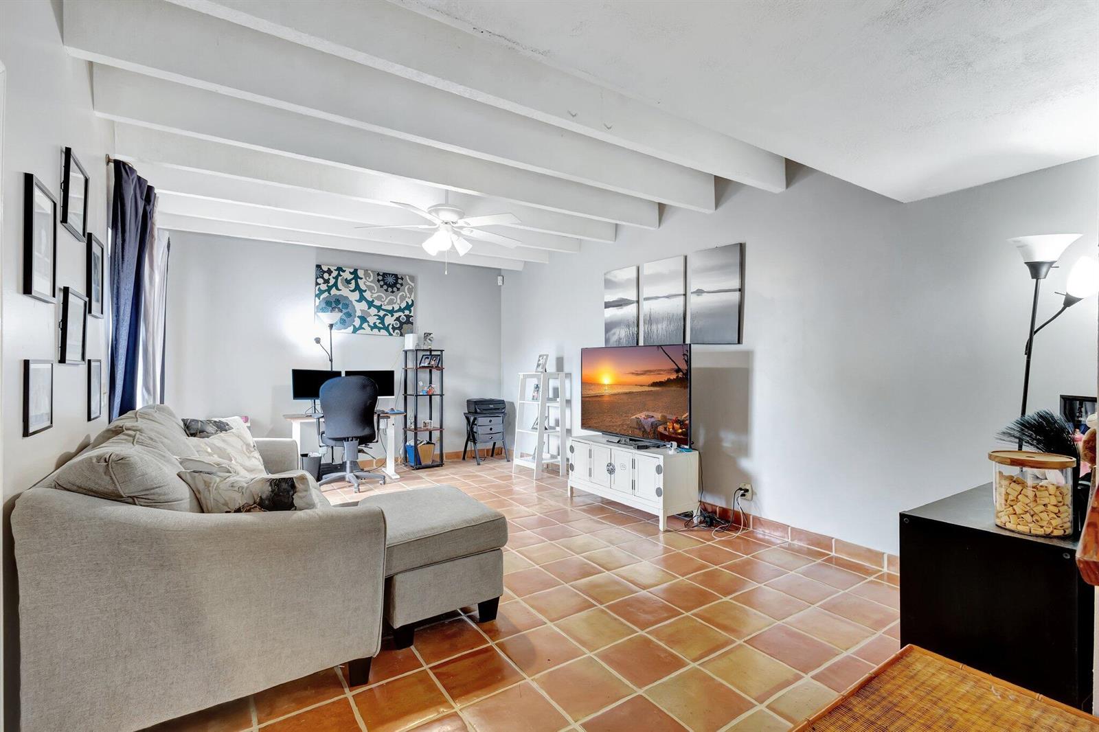 A living room with a gray sectional sofa, television, desk, and terracotta tile flooring — 1586 Shaker Circle, Wellington FL 33414, WELLINGTON, FL