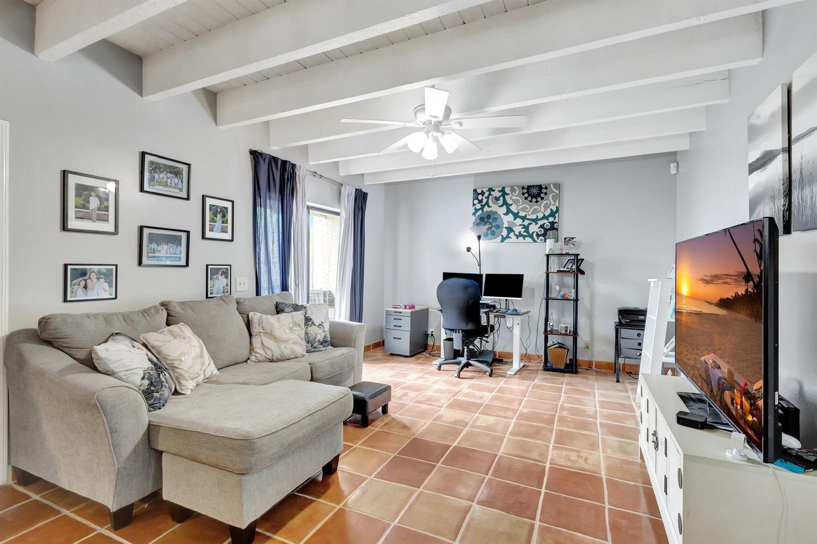 A living room features a gray sectional sofa, a desk area, and terracotta tile flooring — 1586 Shaker Circle, Wellington FL 33414, WELLINGTON, FL