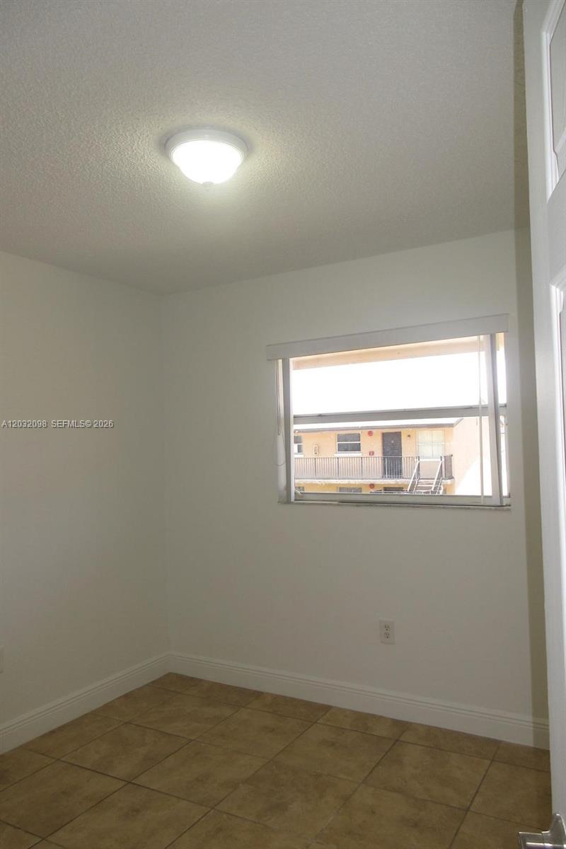 A small room with beige tile flooring, a ceiling light, and a window view — 5461 W 24th Ave # 67, Hialeah FL 33016, HIALEAH, FL