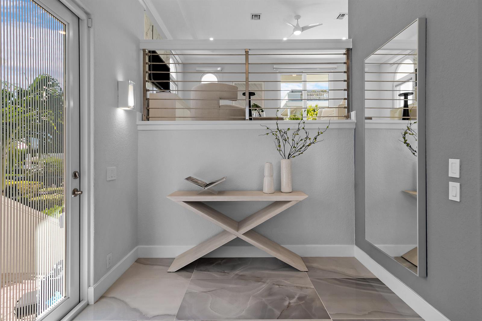 A modern entryway features a light wood console table, a large mirror, and a cable railing — 1792 Bay Drive # 27, Pompano Beach FL 33062, POMPANO BEACH, FL