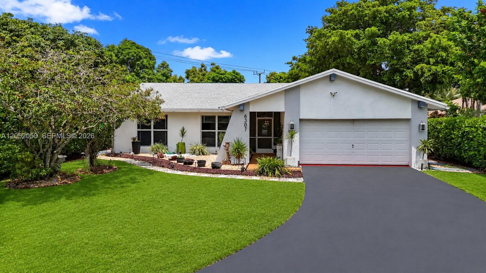 A single-story house features a white exterior, a two-car garage, and a landscaped front yard — 6307 Silk Oak Cir, Tamarac FL 33319, TAMARAC, FL