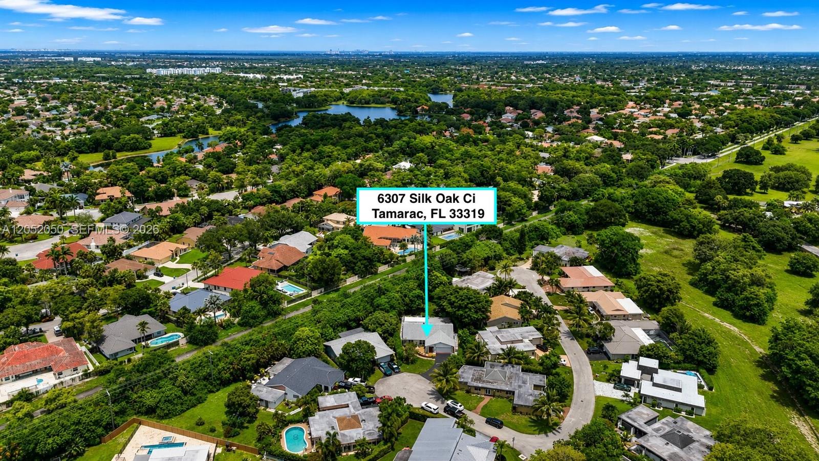 An aerial view shows a single-story house surrounded by lush trees and residential properties — 6307 Silk Oak Cir, Tamarac FL 33319, TAMARAC, FL