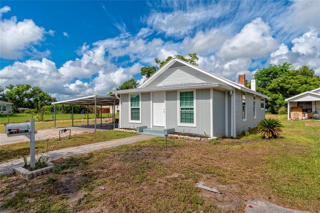 A single-story gray house with a metal carport and a paved walkway in the front — 1812 KENTUCKY AVENUE, ST CLOUD, FL