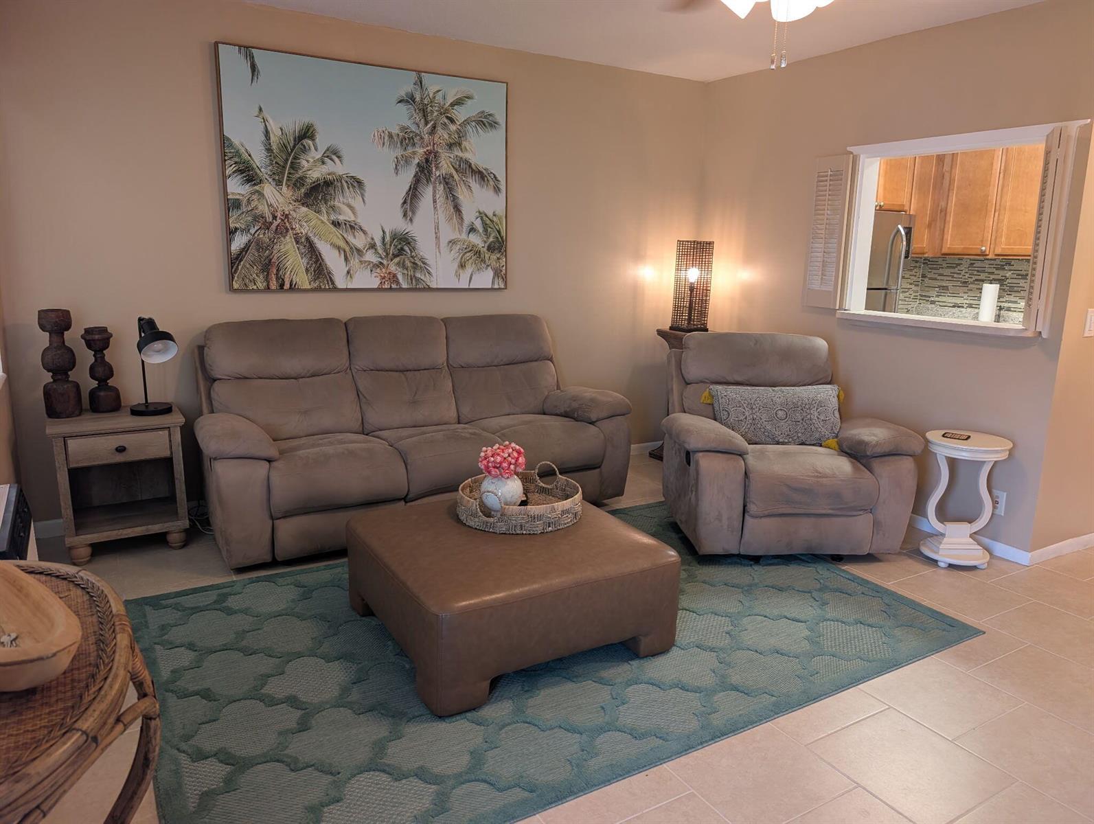 A living room features a sofa, recliner, leather ottoman, and a large palm tree wall print — 190 Easthampton H, West Palm Beach FL 33417, WEST PALM BEACH, FL