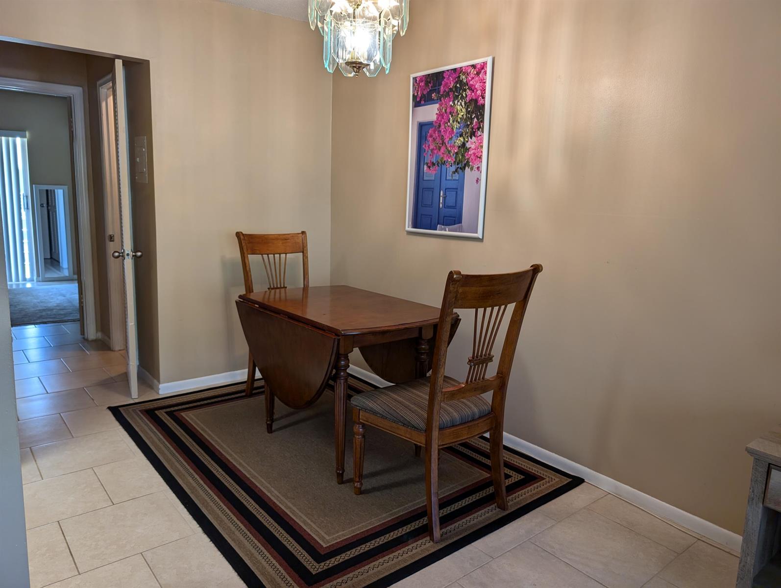 A dining area features a wooden drop-leaf table, two chairs, and a wall-mounted floral print — 190 Easthampton H, West Palm Beach FL 33417, WEST PALM BEACH, FL