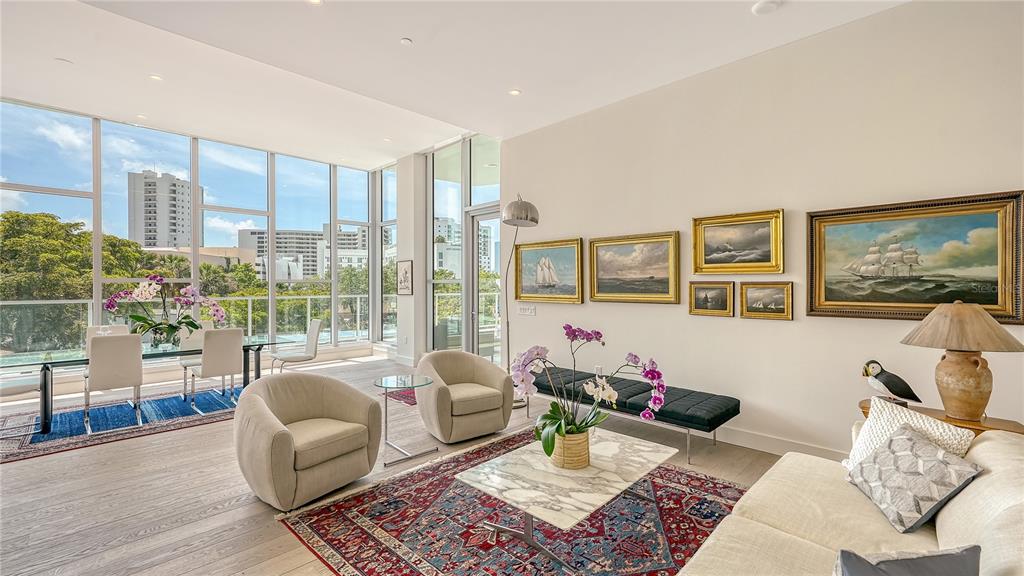 A bright living and dining area features floor-to-ceiling windows, hardwood floors, and a gallery wall — 1335 2ND STREET UNIT Villa 2E, SARASOTA, FL