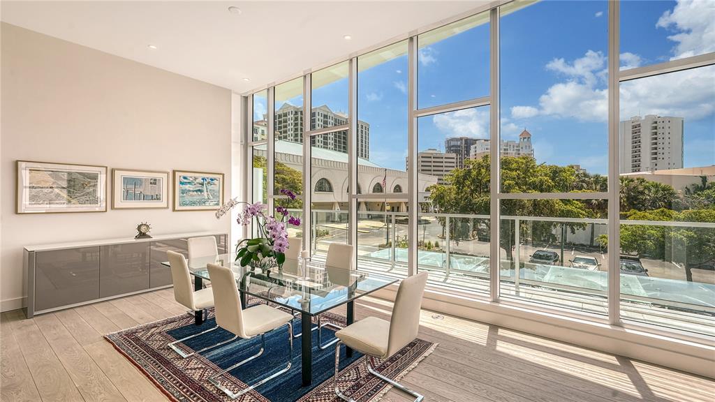A dining room with a glass table, modern chairs, and floor-to-ceiling windows overlooking a city — 1335 2ND STREET UNIT Villa 2E, SARASOTA, FL