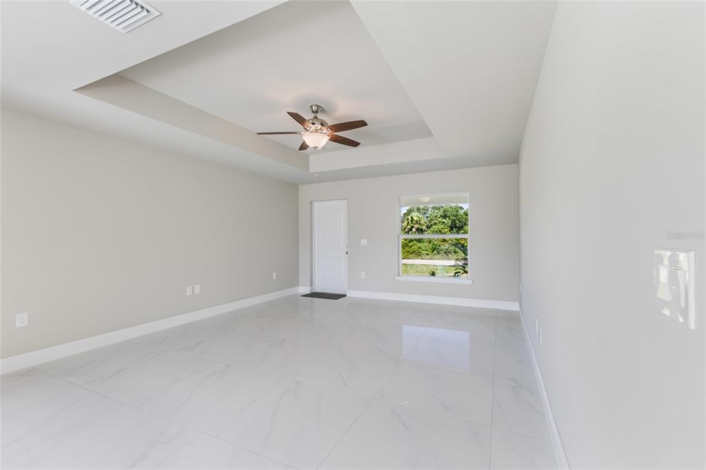 A bright room with white tile flooring, a tray ceiling, and a ceiling fan — 1964 LEGHORN STREET, LEHIGH ACRES, FL