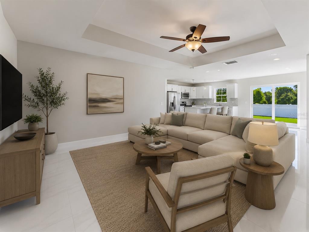 This living room features a sectional sofa, a coffee table, and an open-concept kitchen — 1964 LEGHORN STREET, LEHIGH ACRES, FL