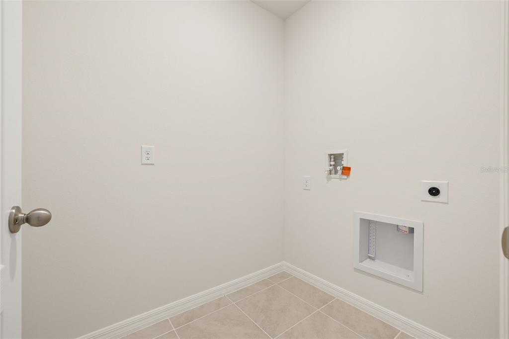 An empty laundry room with tile flooring, a utility box, and wall-mounted electrical outlets — 2842 WATERLILY WAY, KISSIMMEE, FL