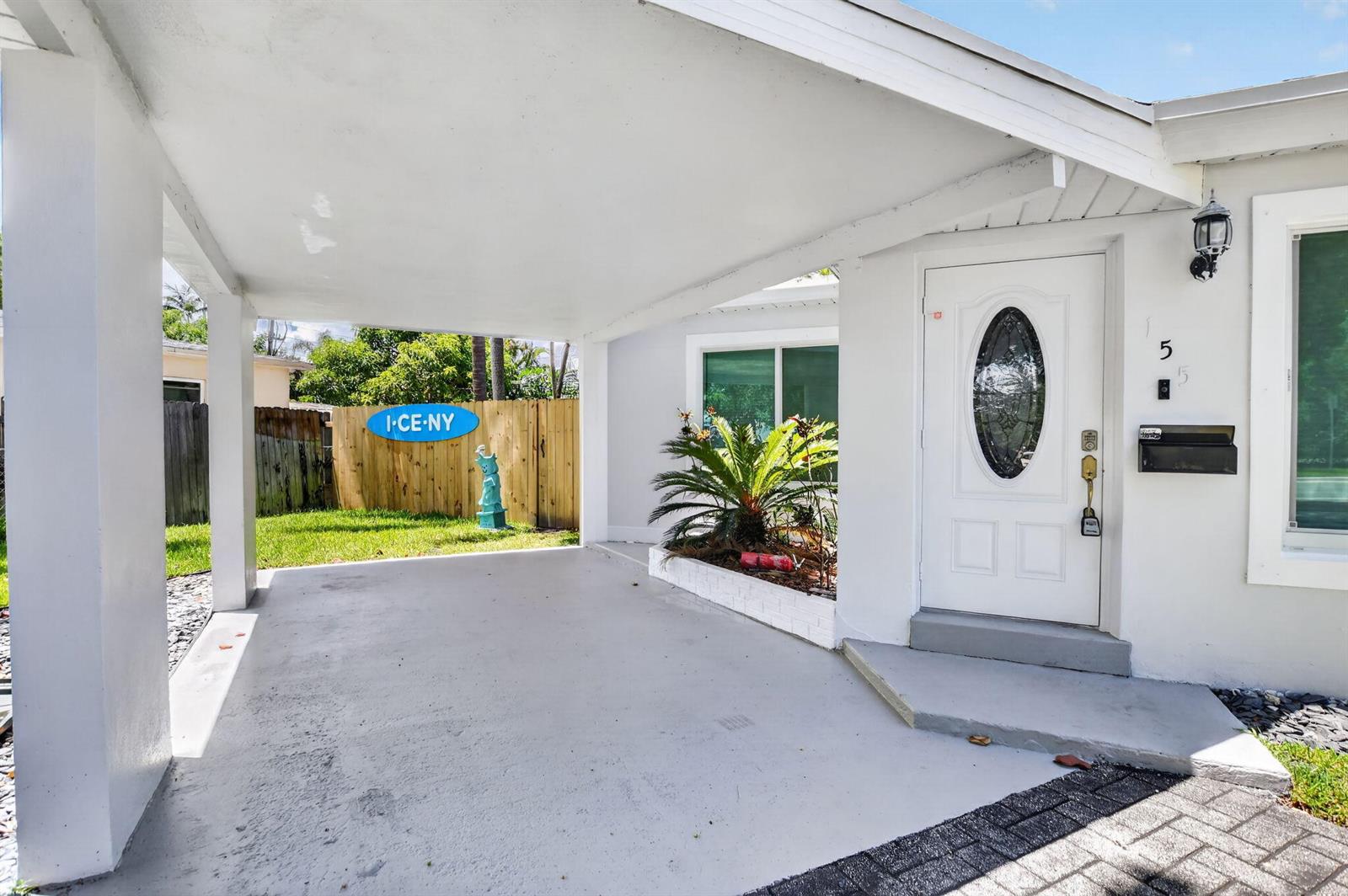 A white house exterior features a covered carport, a front door, and a small garden — 155 NE 20th Street, Boca Raton FL 33431, BOCA RATON, FL