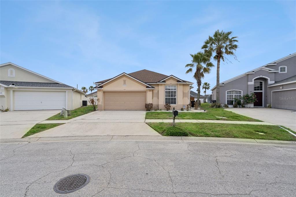 A single-story suburban house with a tan exterior, a two-car garage, and palm trees — 170 BLOOMINGDALE DRIVE, DAVENPORT, FL