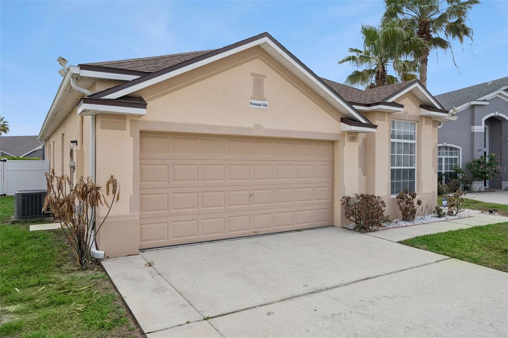 A beige single-story house with a two-car garage and a concrete driveway — 170 BLOOMINGDALE DRIVE, DAVENPORT, FL