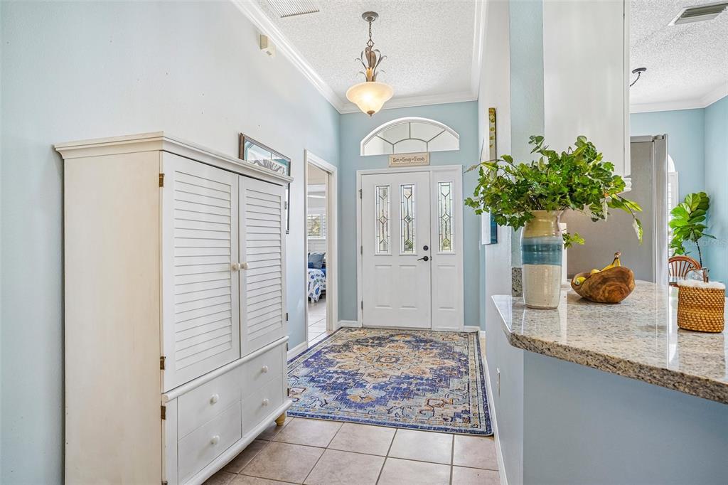 An entryway features a white cabinet, a patterned area rug, and a front door — 2837 GRANT WAY, THE VILLAGES, FL