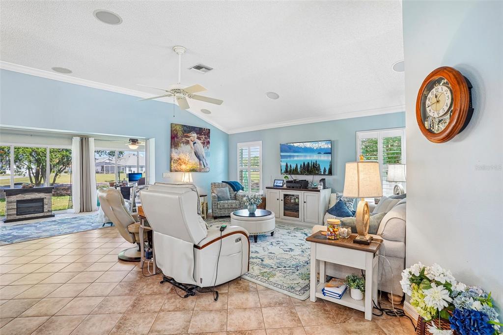 A living room features light blue walls, tile flooring, a ceiling fan, and a television — 2837 GRANT WAY, THE VILLAGES, FL