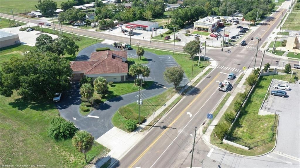 An aerial view shows a commercial building with a parking lot near a road intersection — 695 N SCENIC HIGHWAY, FROSTPROOF, FL