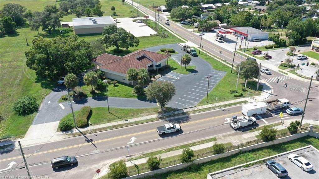 An aerial view shows a commercial building with a parking lot situated near a road intersection — 695 N SCENIC HIGHWAY, FROSTPROOF, FL