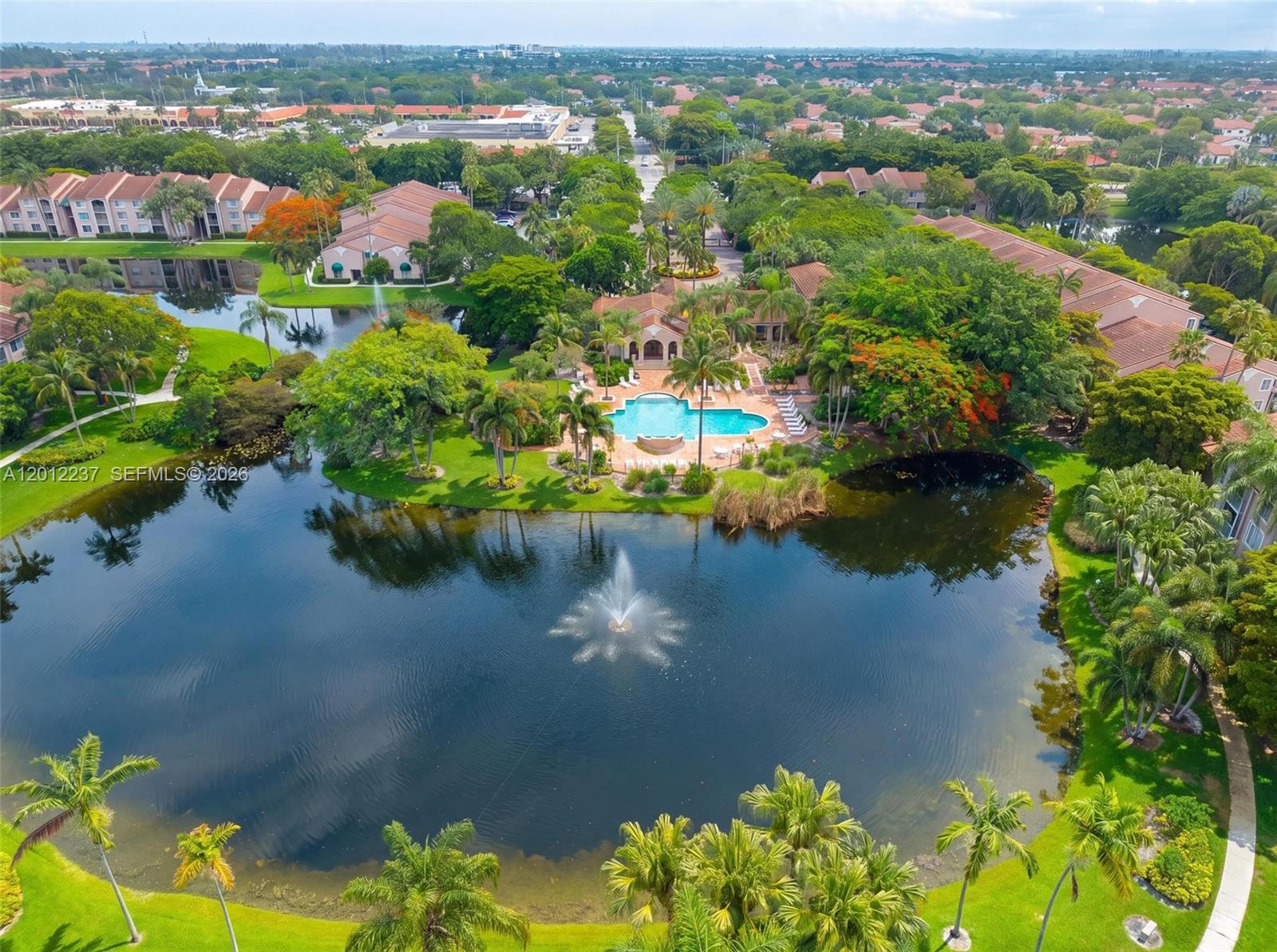 An aerial view shows a residential complex with a central swimming pool and a fountain — MIRAMAR, FL