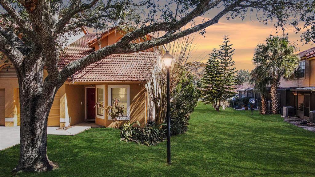 A tan house with a red tile roof sits next to a grassy lawn — 1192 N FAIRWAY DRIVE, APOPKA, FL