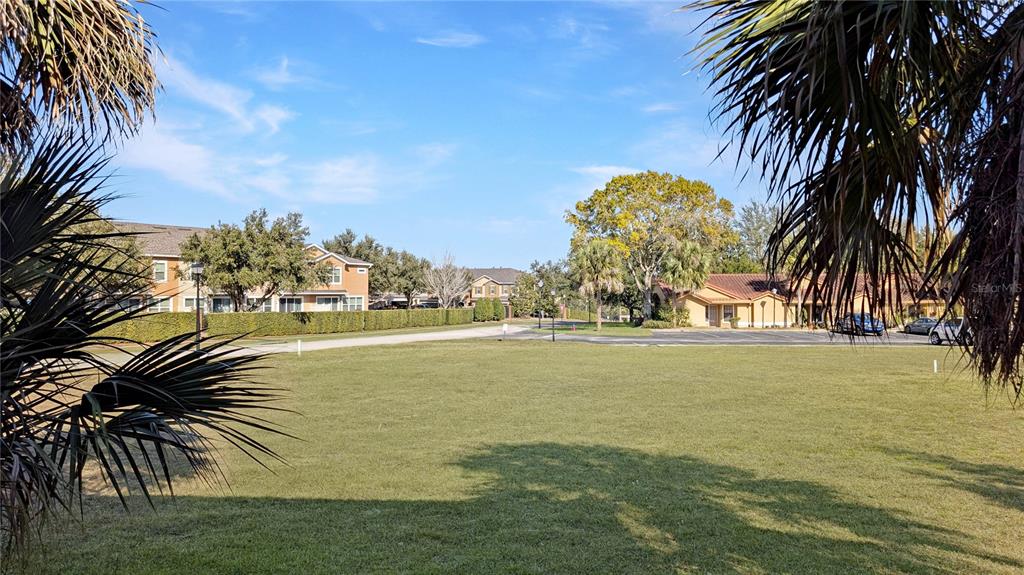 A grassy field sits in front of multi-story residential buildings under a clear blue sky — 1192 N FAIRWAY DRIVE, APOPKA, FL