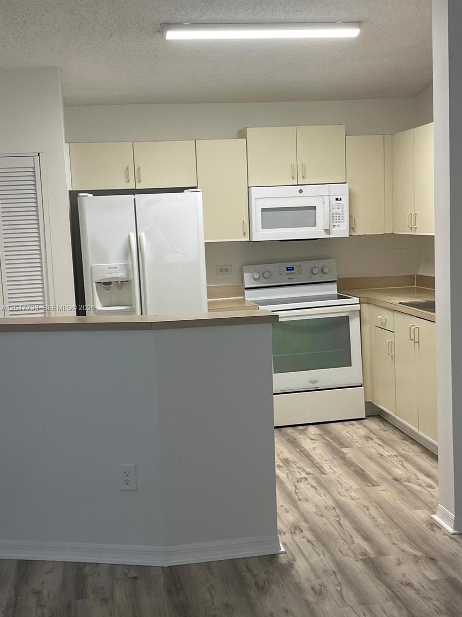 A kitchen features white appliances, light-colored cabinets, and wood-look flooring — 3660 N 56th Ave # 601, Hollywood FL 33021, HOLLYWOOD, FL
