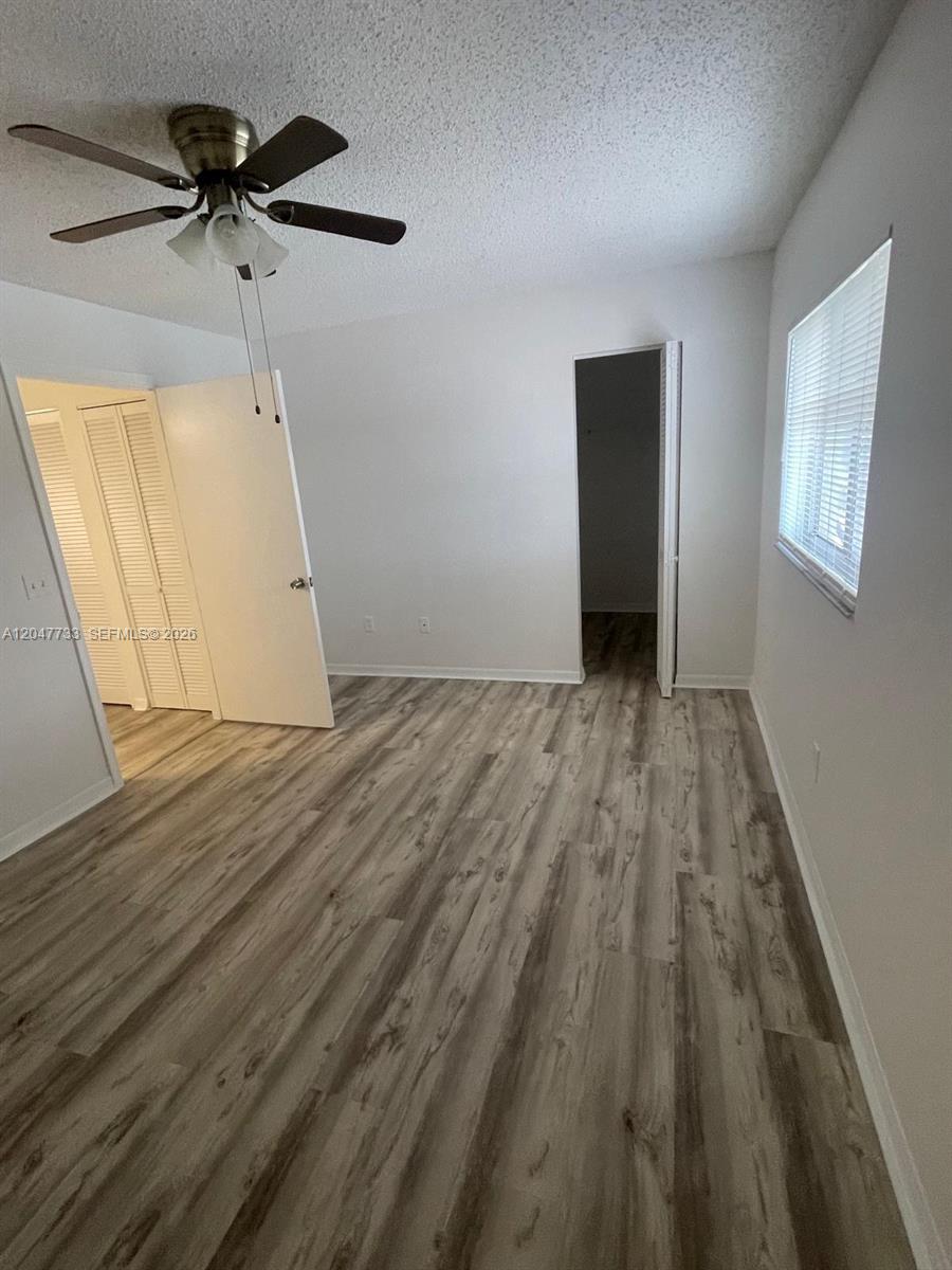 A bedroom features light wood-look flooring, white walls, a ceiling fan, and two open doorways — 3660 N 56th Ave # 601, Hollywood FL 33021, HOLLYWOOD, FL