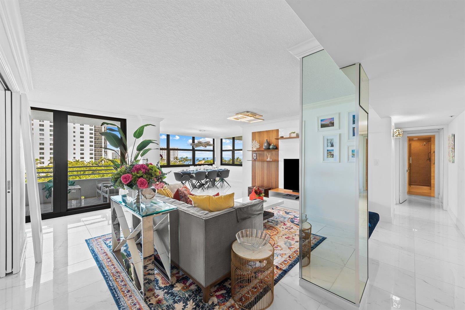 A bright living room features white tile floors, a mirrored column, and a balcony view — 3450 S Ocean Boulevard # 605, Highland Beach FL 33487, HIGHLAND BEACH, FL