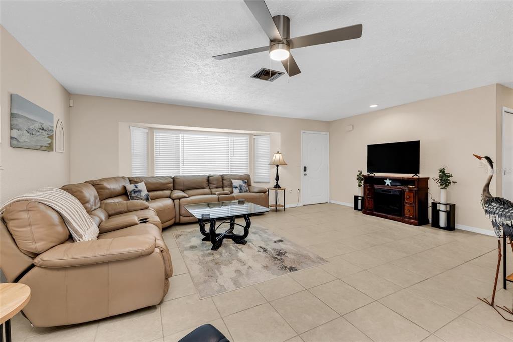 A living room features a large tan sectional sofa, a glass coffee table, and tile flooring — 82 ROTONDA CIRCLE, ROTONDA WEST, FL
