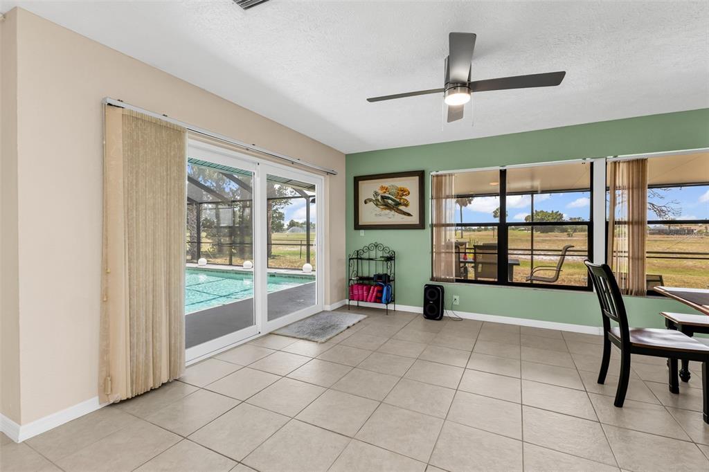 A sunroom with tile flooring, a ceiling fan, and sliding glass doors overlooking a pool — 82 ROTONDA CIRCLE, ROTONDA WEST, FL