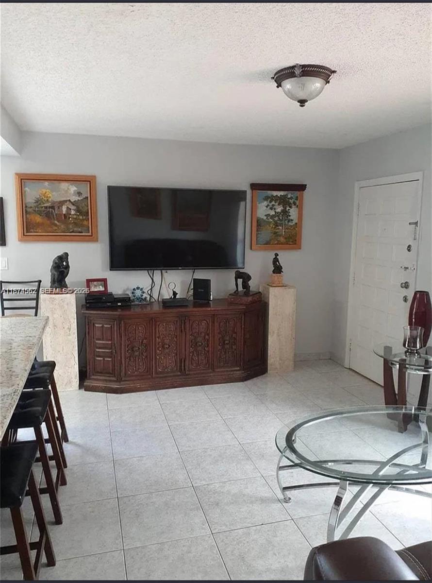 A living room features a large television on a wooden cabinet, artwork, and tile flooring — 9360 SW 37th St, Miami FL 33165, MIAMI, FL