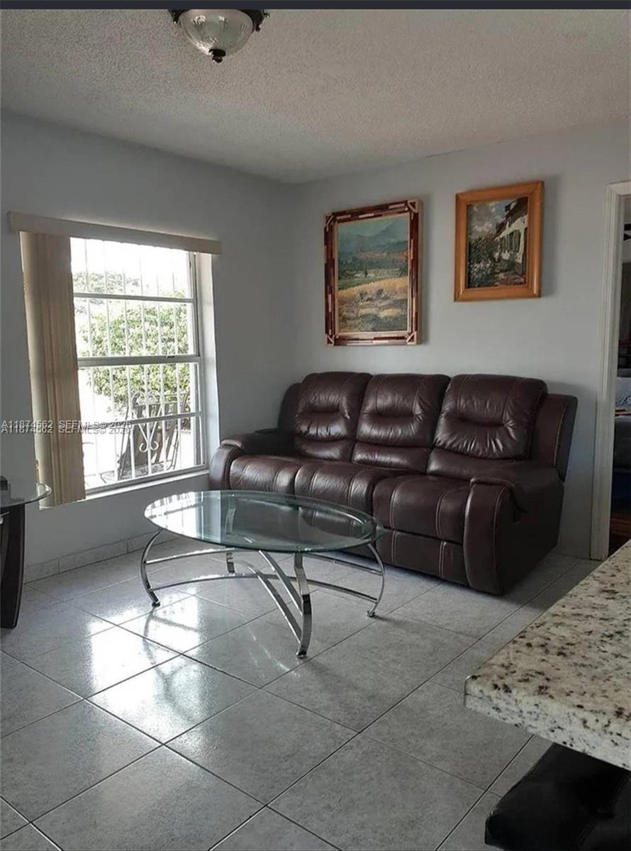 A living room features a brown leather sofa, a glass coffee table, and tiled floors — 9360 SW 37th St, Miami FL 33165, MIAMI, FL
