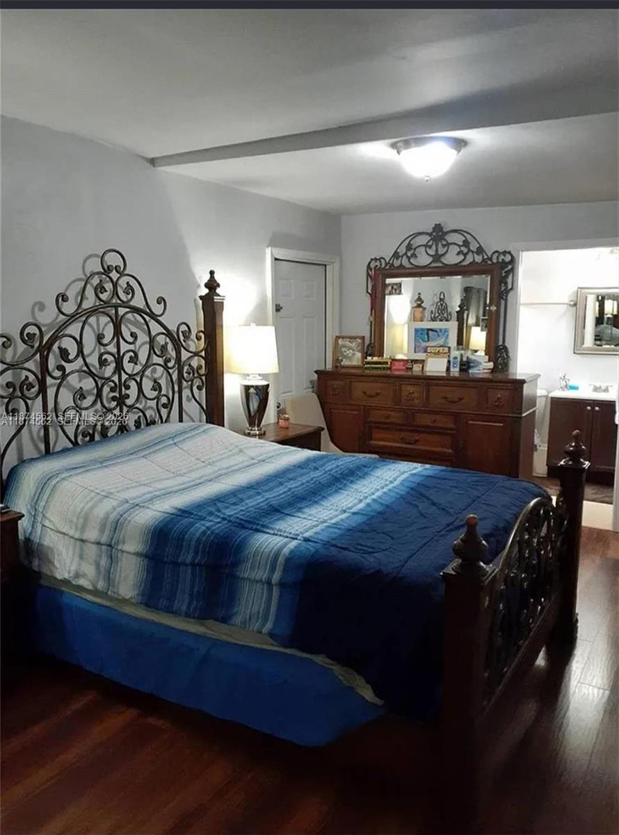 A bedroom features a wrought iron headboard, a wooden dresser with a mirror, and wood flooring — 9360 SW 37th St, Miami FL 33165, MIAMI, FL