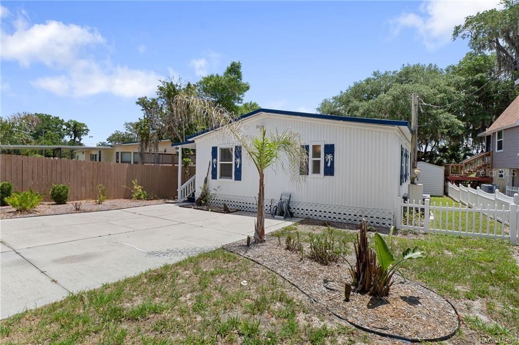 A single-story mobile home with white siding, blue shutters, and a concrete driveway — 4190 E LAKE PARK DRIVE, HERNANDO, FL