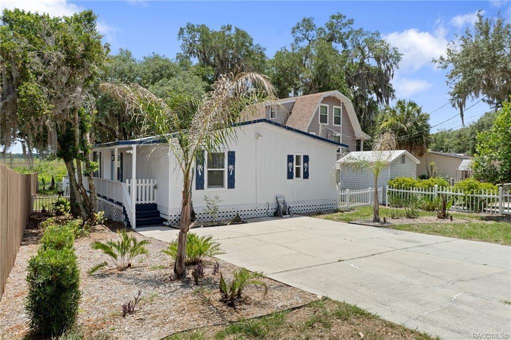 A white mobile home with blue shutters and a front porch sits on a concrete driveway — 4190 E LAKE PARK DRIVE, HERNANDO, FL