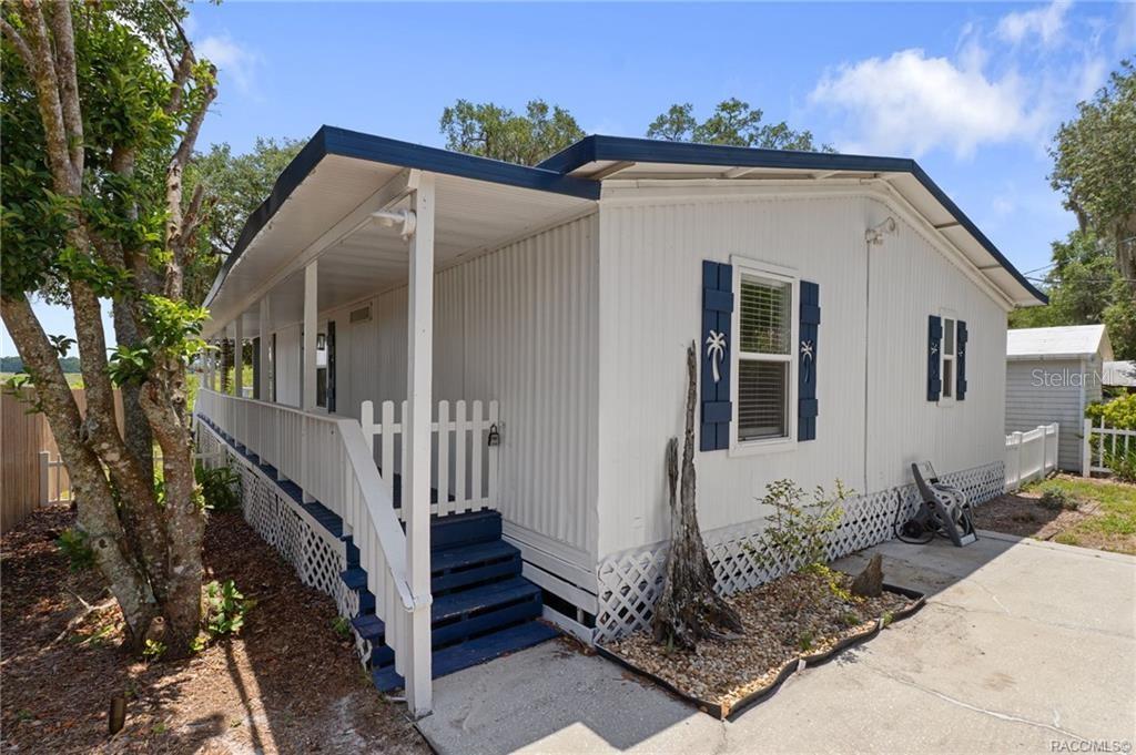 A white mobile home features a covered front porch with blue stairs and blue shutters — 4190 E LAKE PARK DRIVE, HERNANDO, FL