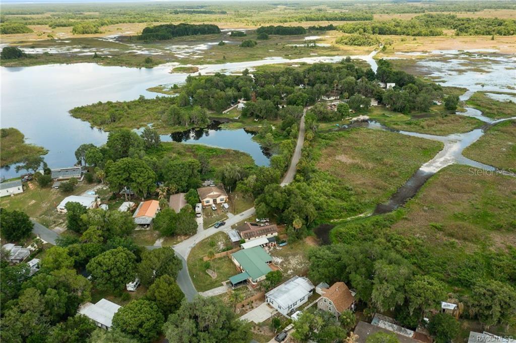 An aerial view shows houses situated along a road surrounded by wetlands and water — 4190 E LAKE PARK DRIVE, HERNANDO, FL
