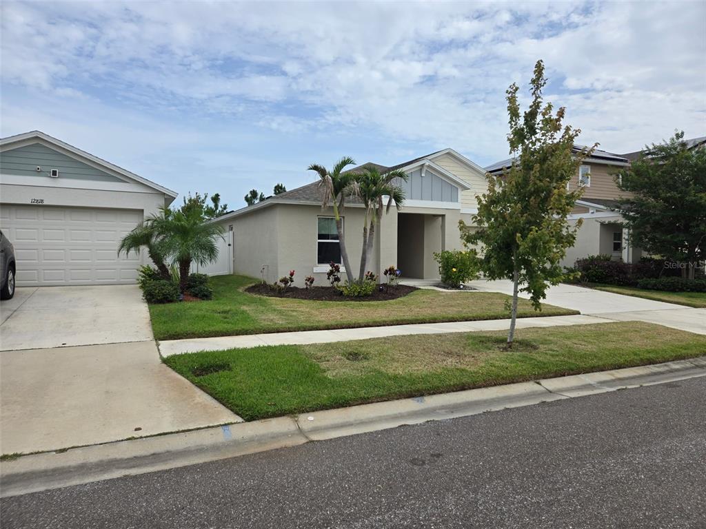 A single-story suburban house with a tan exterior, a two-car garage, and palm trees — 12820 BENT TWIG DRIVE, RIVERVIEW, FL