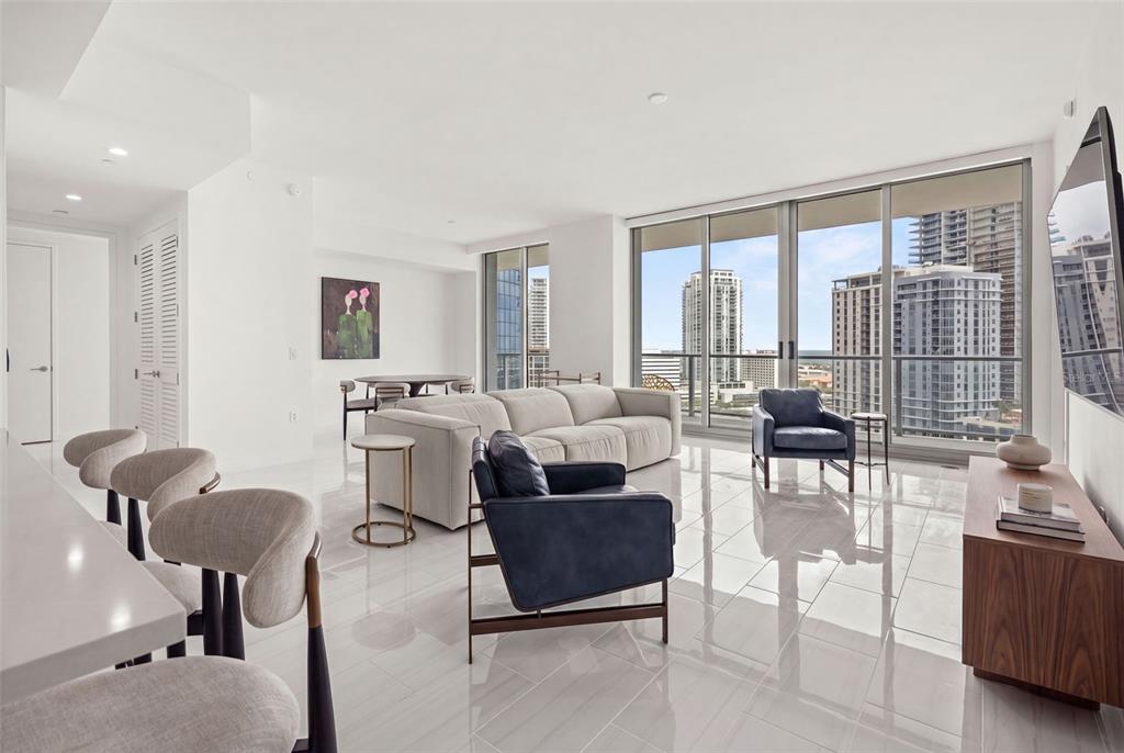 A modern living and dining area with white floors, a sectional sofa, and floor-to-ceiling windows — 400 CENTRAL AVENUE UNIT 1405, ST PETERSBURG, FL
