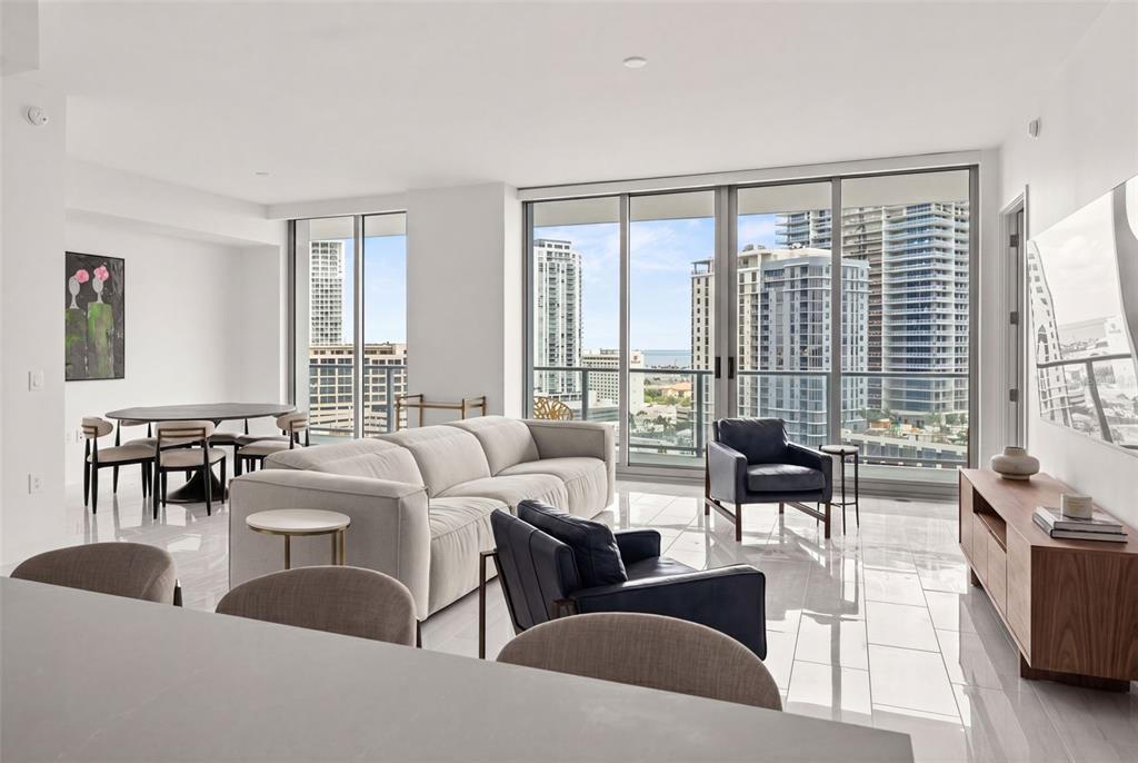 A modern living room with white tile floors, a beige sofa, and floor-to-ceiling windows — 400 CENTRAL AVENUE UNIT 1405, ST PETERSBURG, FL