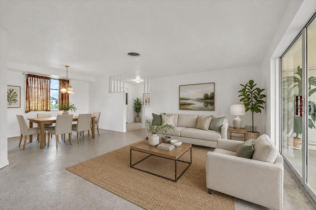 A bright, open-concept living and dining area features neutral furniture, a jute rug, and concrete floors — 3395 PINETREE STREET, PORT CHARLOTTE, FL